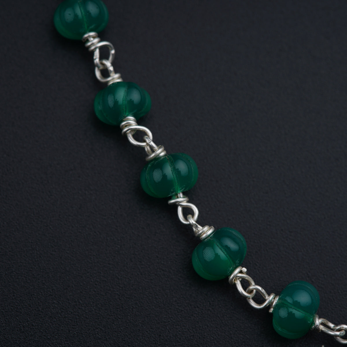 a close up of a bracelet with green beads