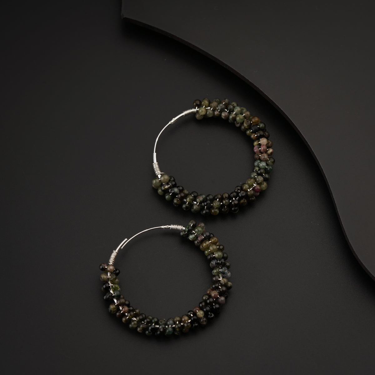 a pair of beaded hoop earrings sitting on top of a table
