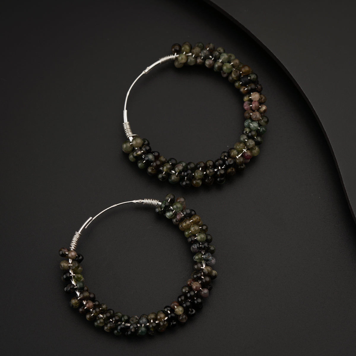 a pair of beaded hoop earrings sitting on top of a table