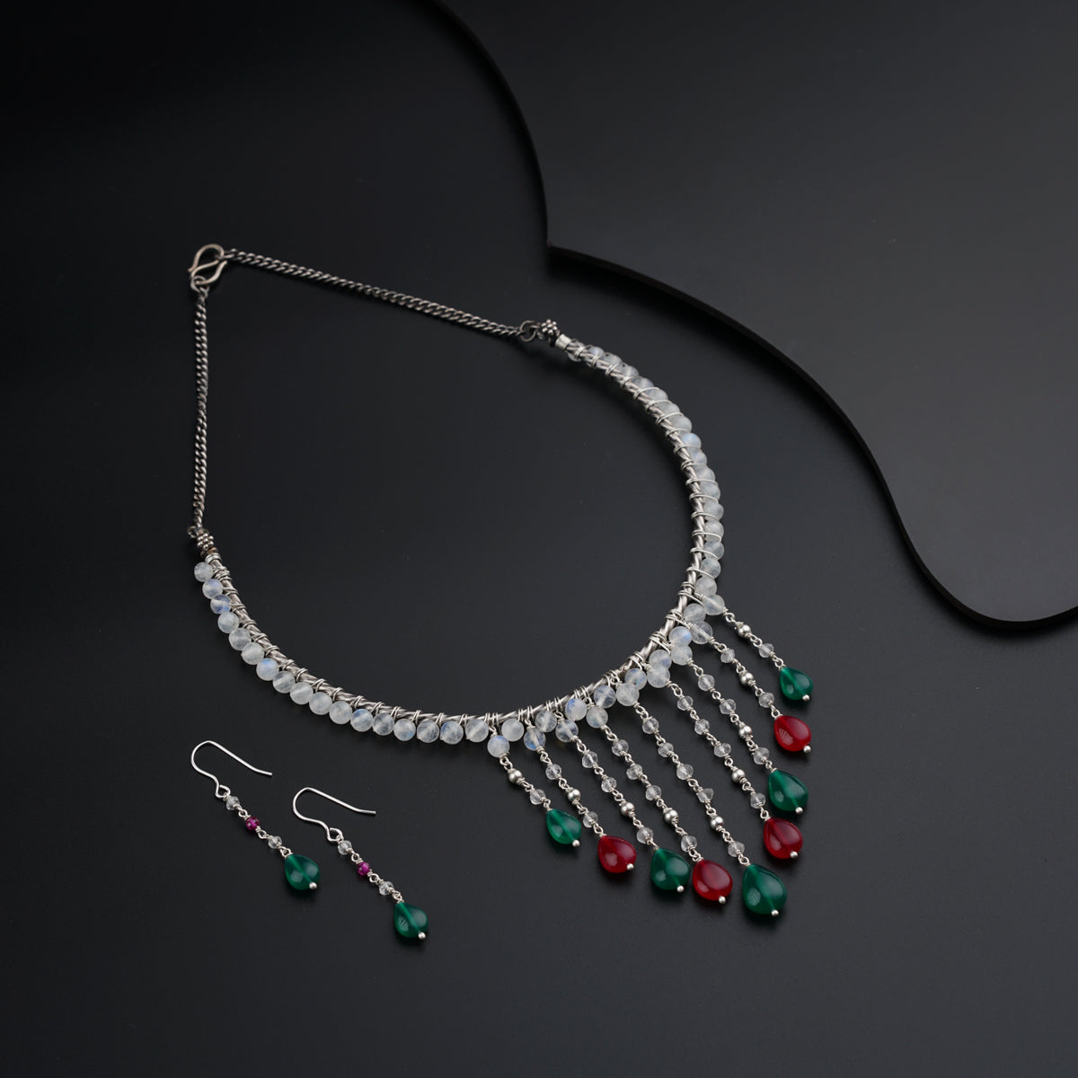a necklace and earring set on a black surface