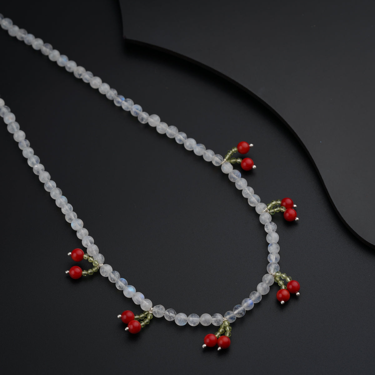 a necklace with beads and red berries on it