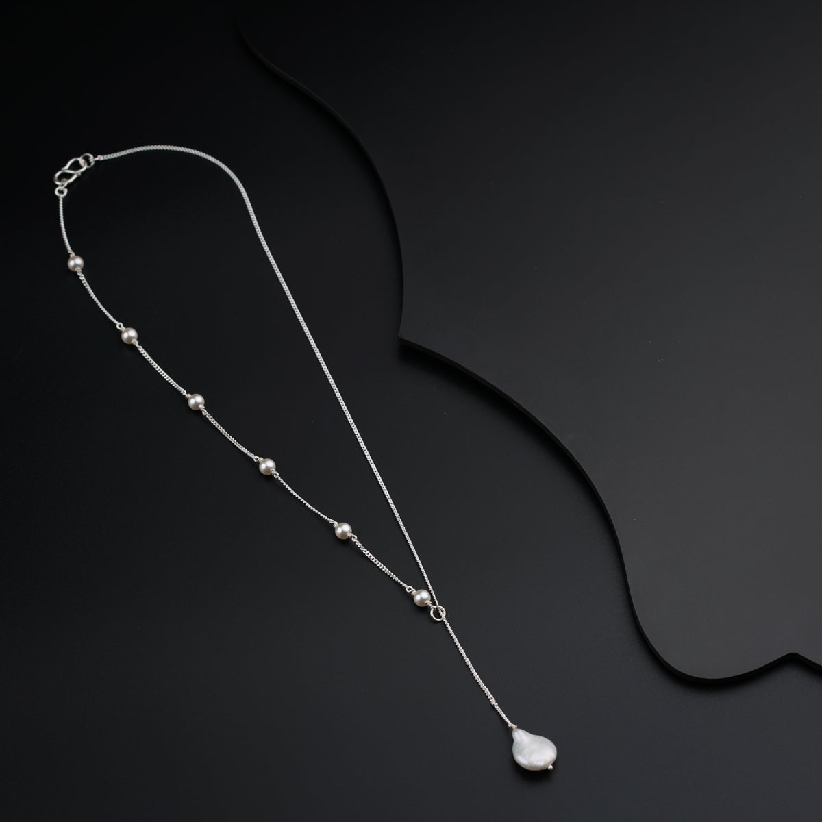 a long necklace with a white stone on a black background