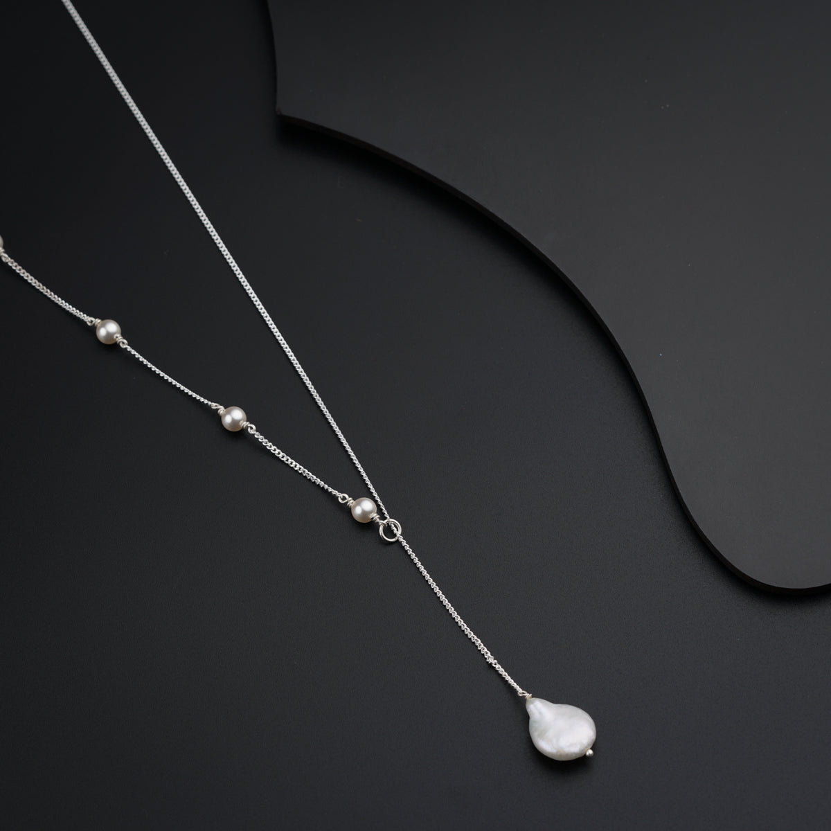 a necklace with a white pearl on a black background