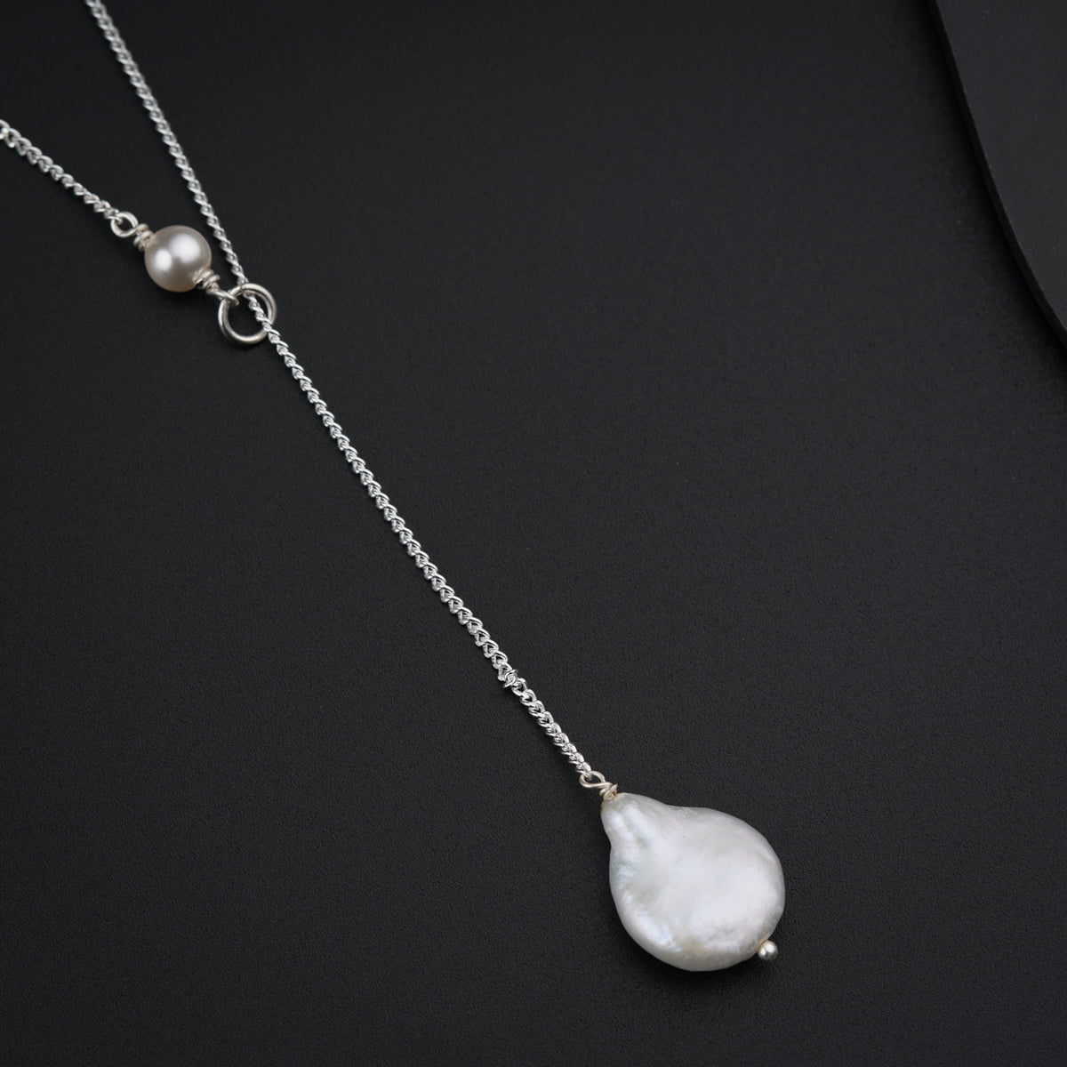 a necklace with a white pearl hanging from it