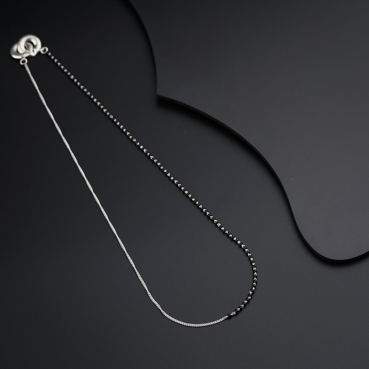 a black and white photo of a necklace on a black surface