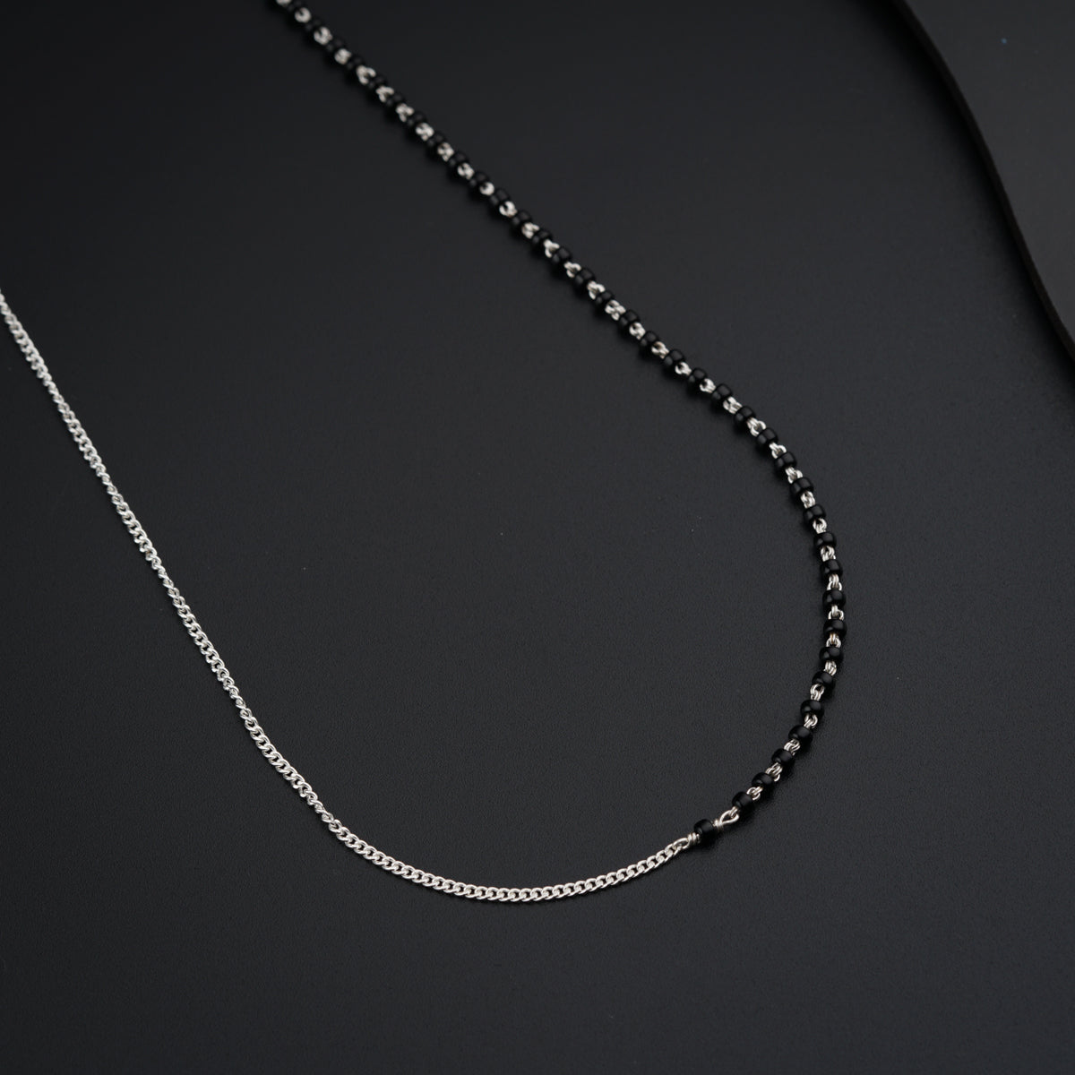 a black and silver necklace on a black surface