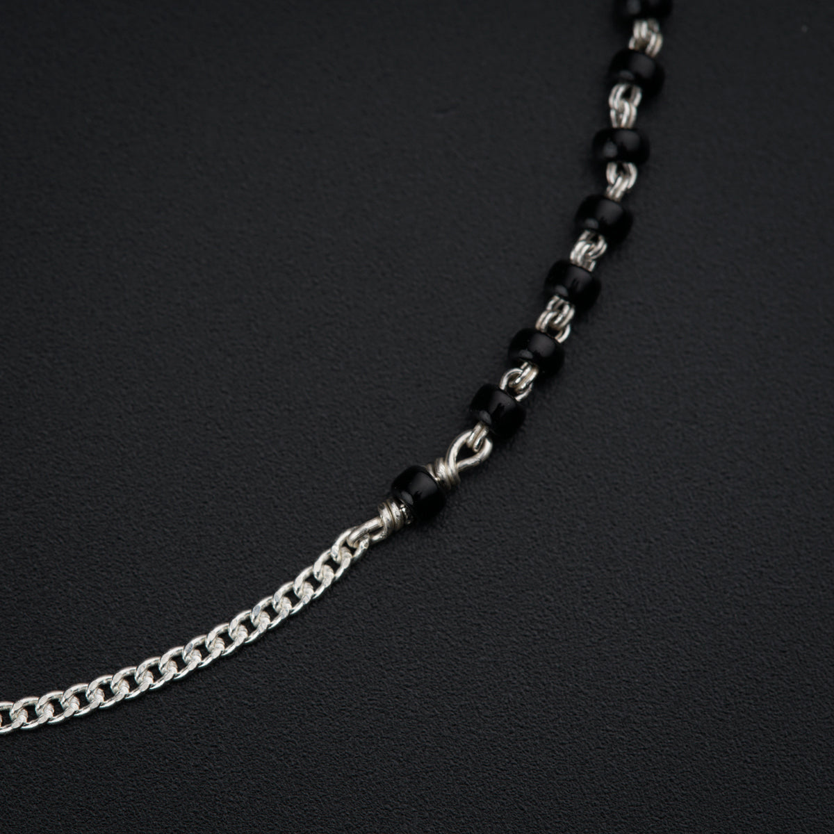a black and silver chain is on a black surface