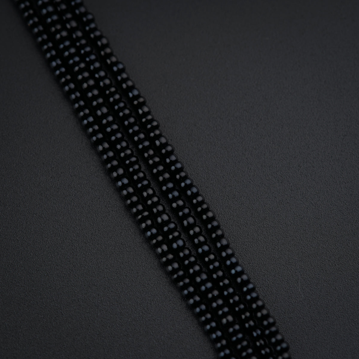three strands of black beads on a black surface