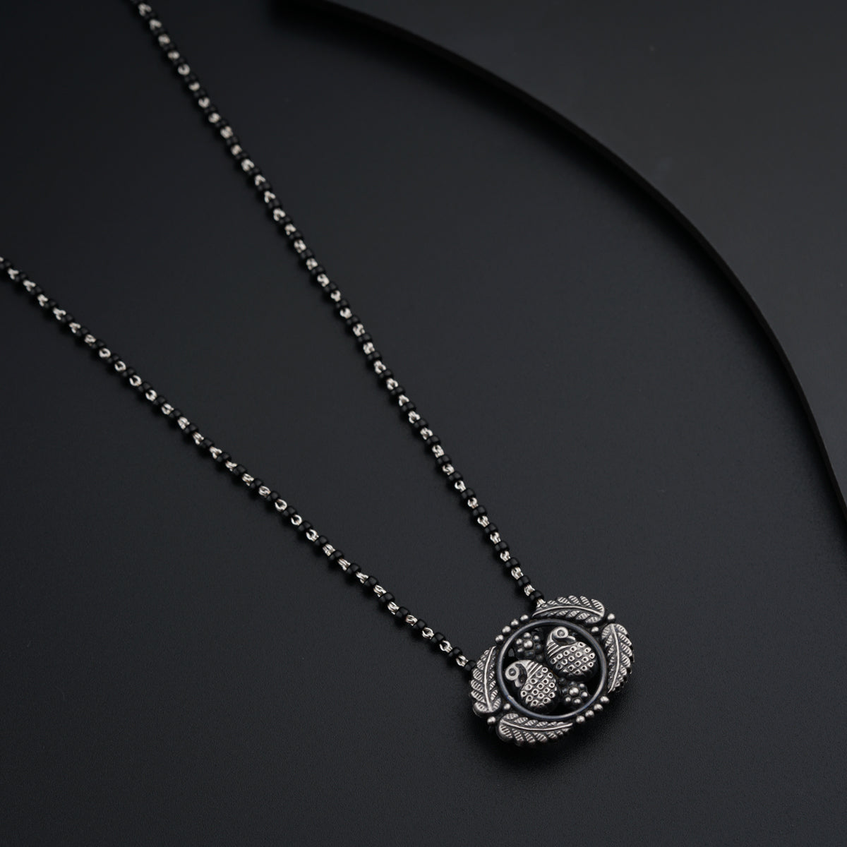 a black and white photo of a necklace on a black surface
