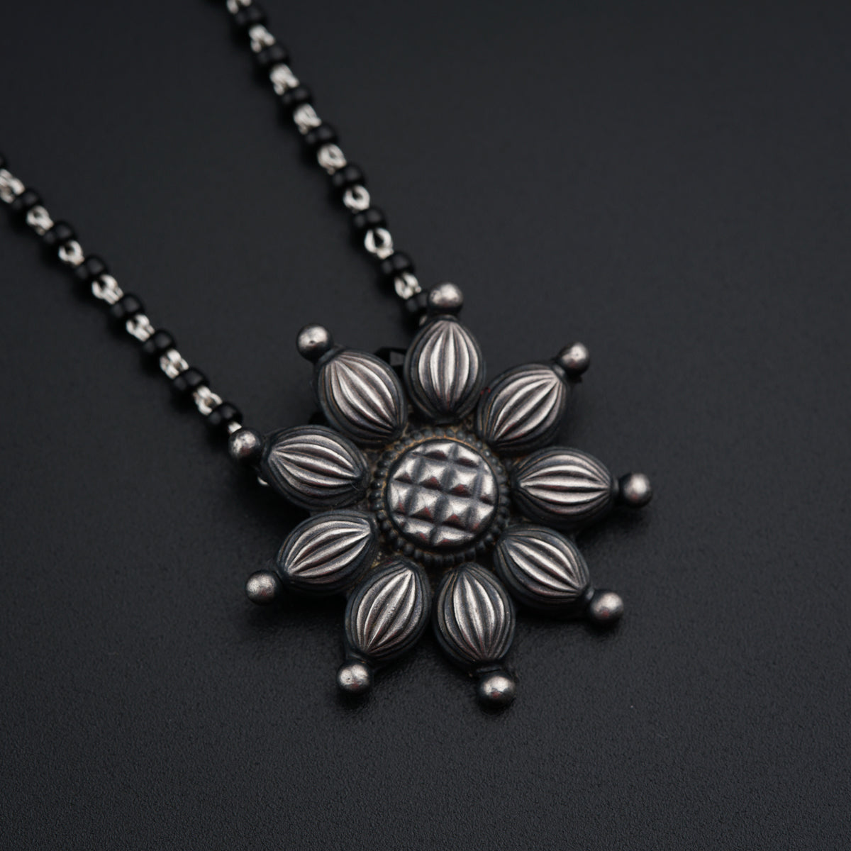 a black and silver necklace with a flower design