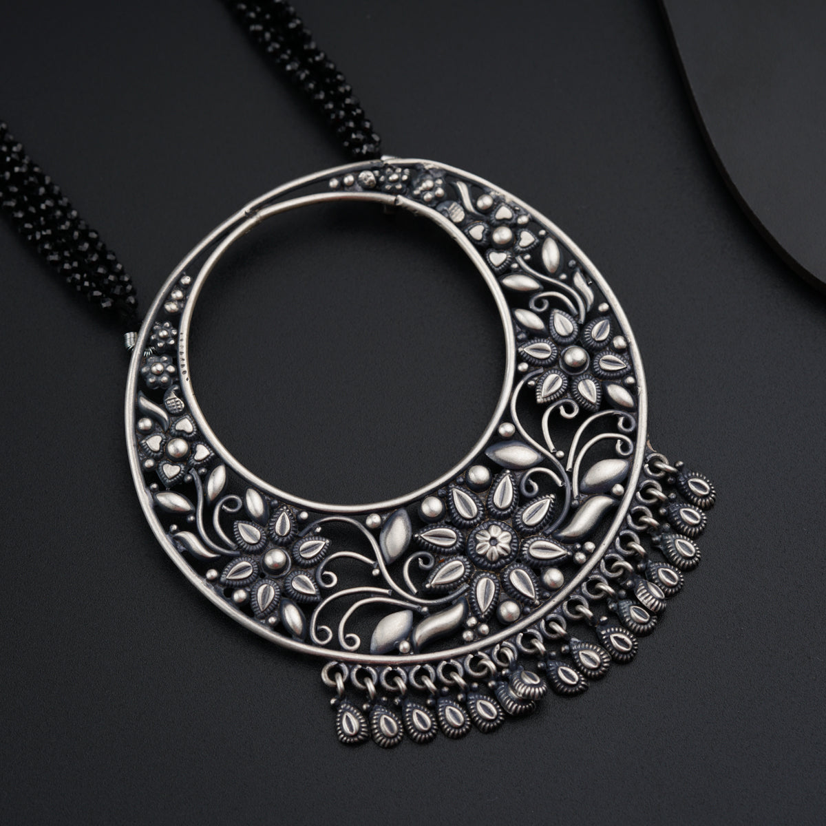 a necklace with a circular design on a black background