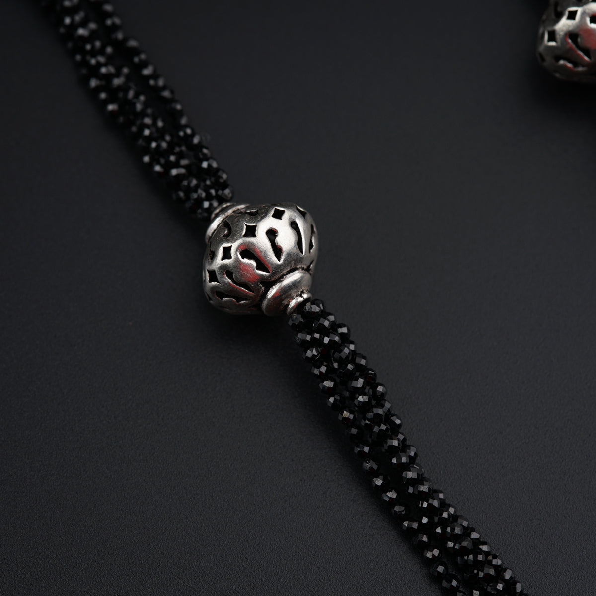 a black beaded necklace with a silver bead