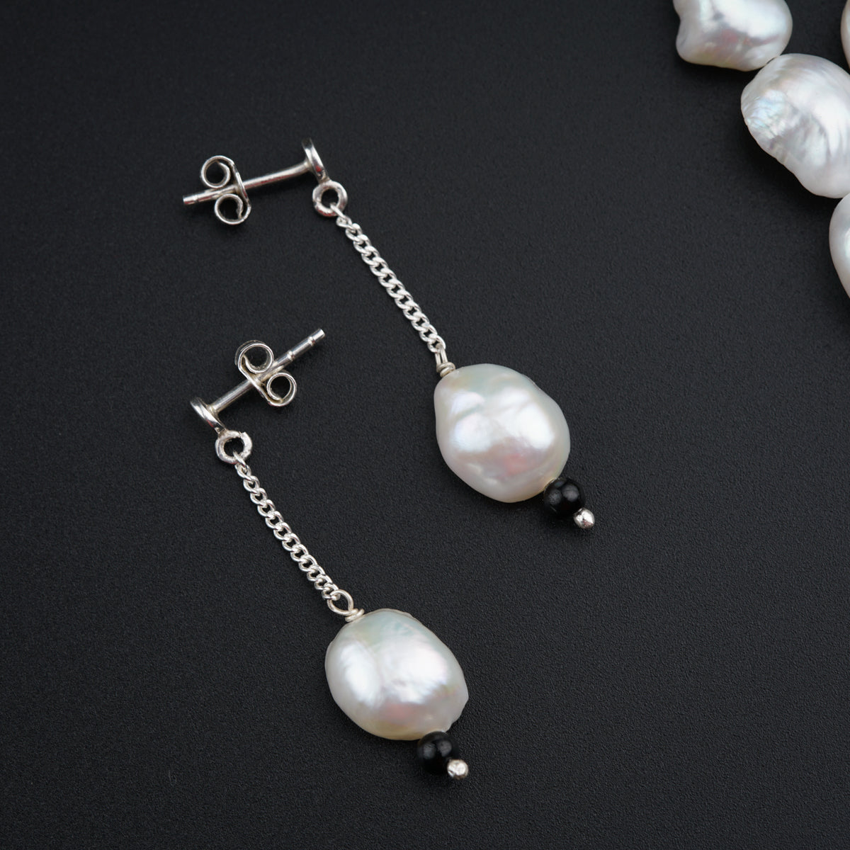 a pair of earrings with pearls hanging from them