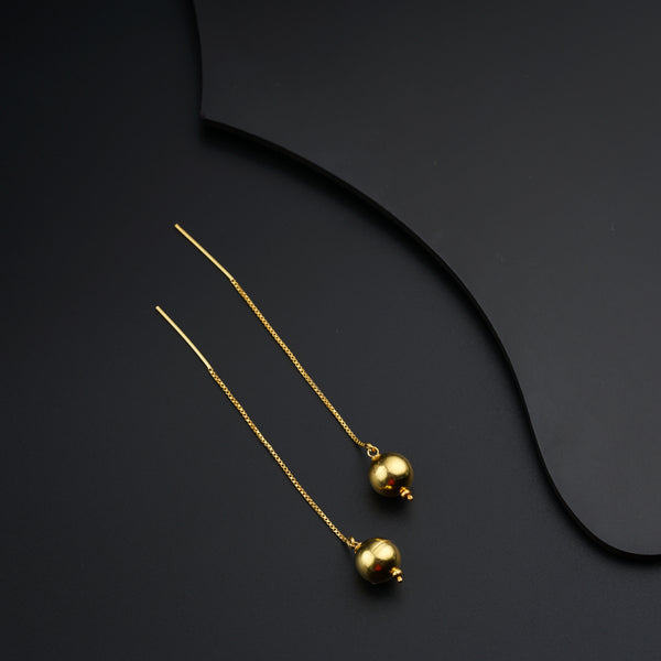 a pair of gold earrings on a black surface
