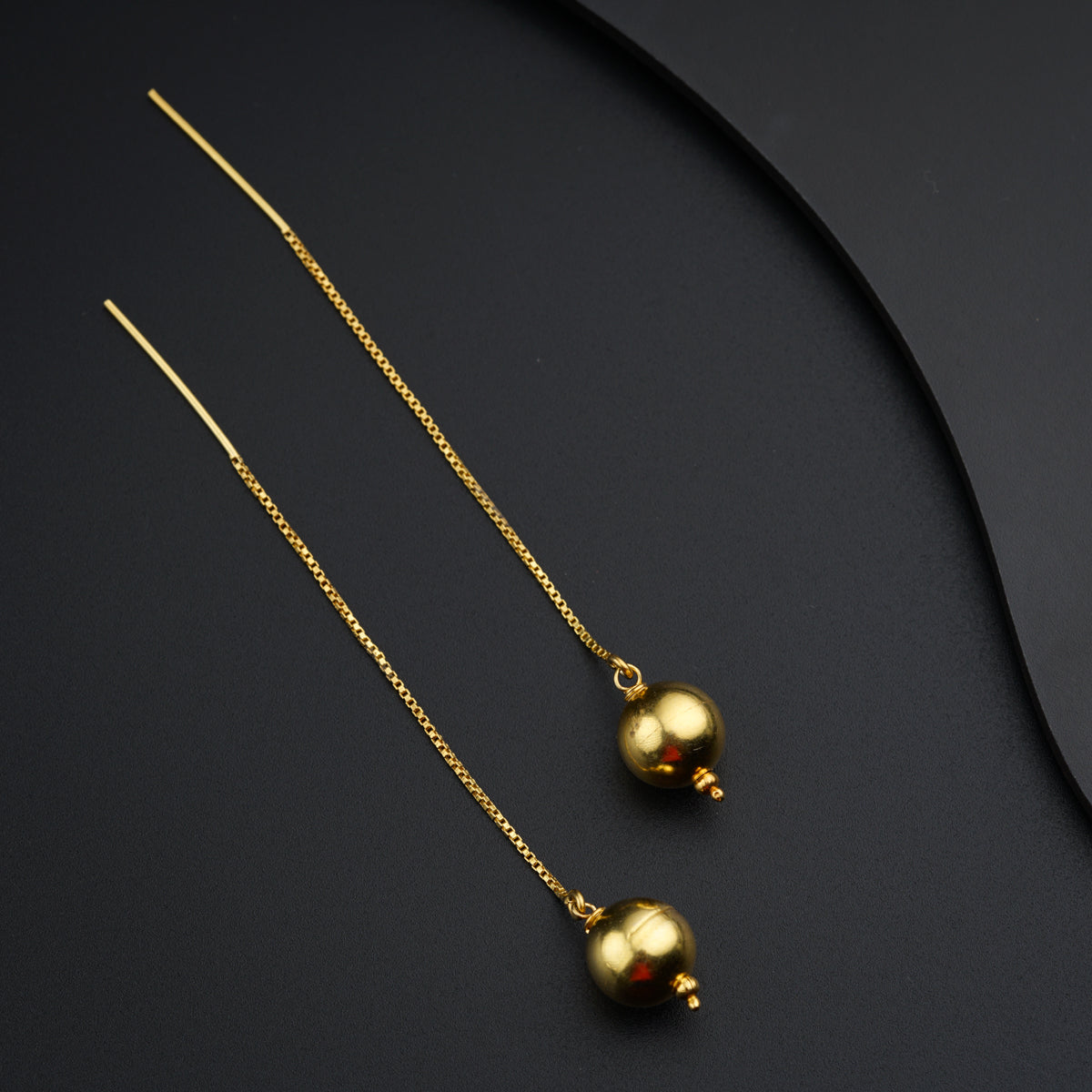 a pair of gold necklaces on a black surface