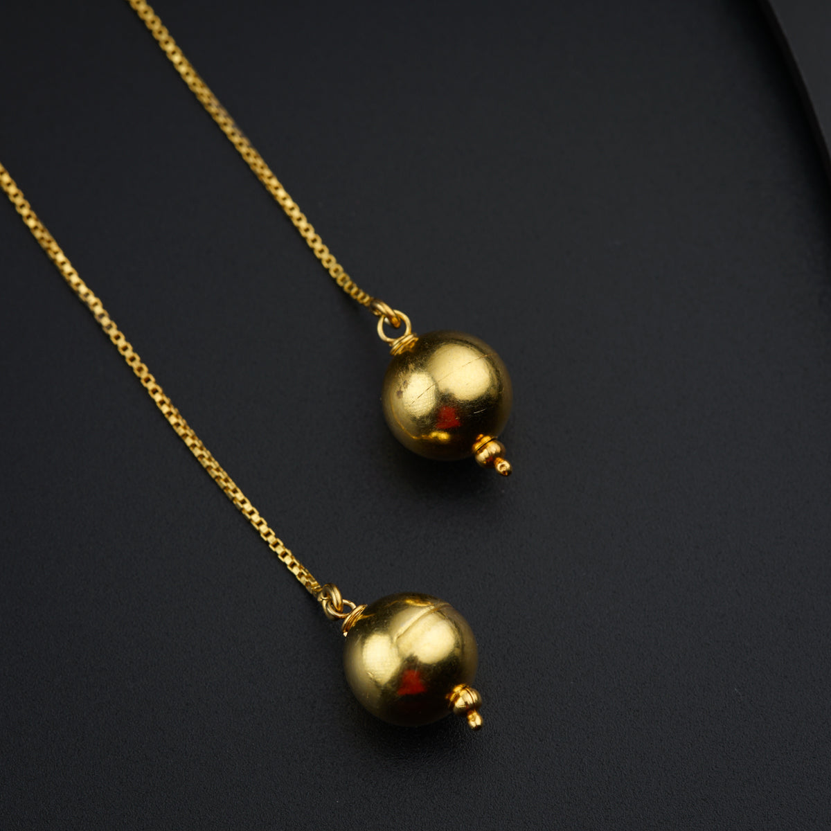 a pair of gold necklaces on a black surface
