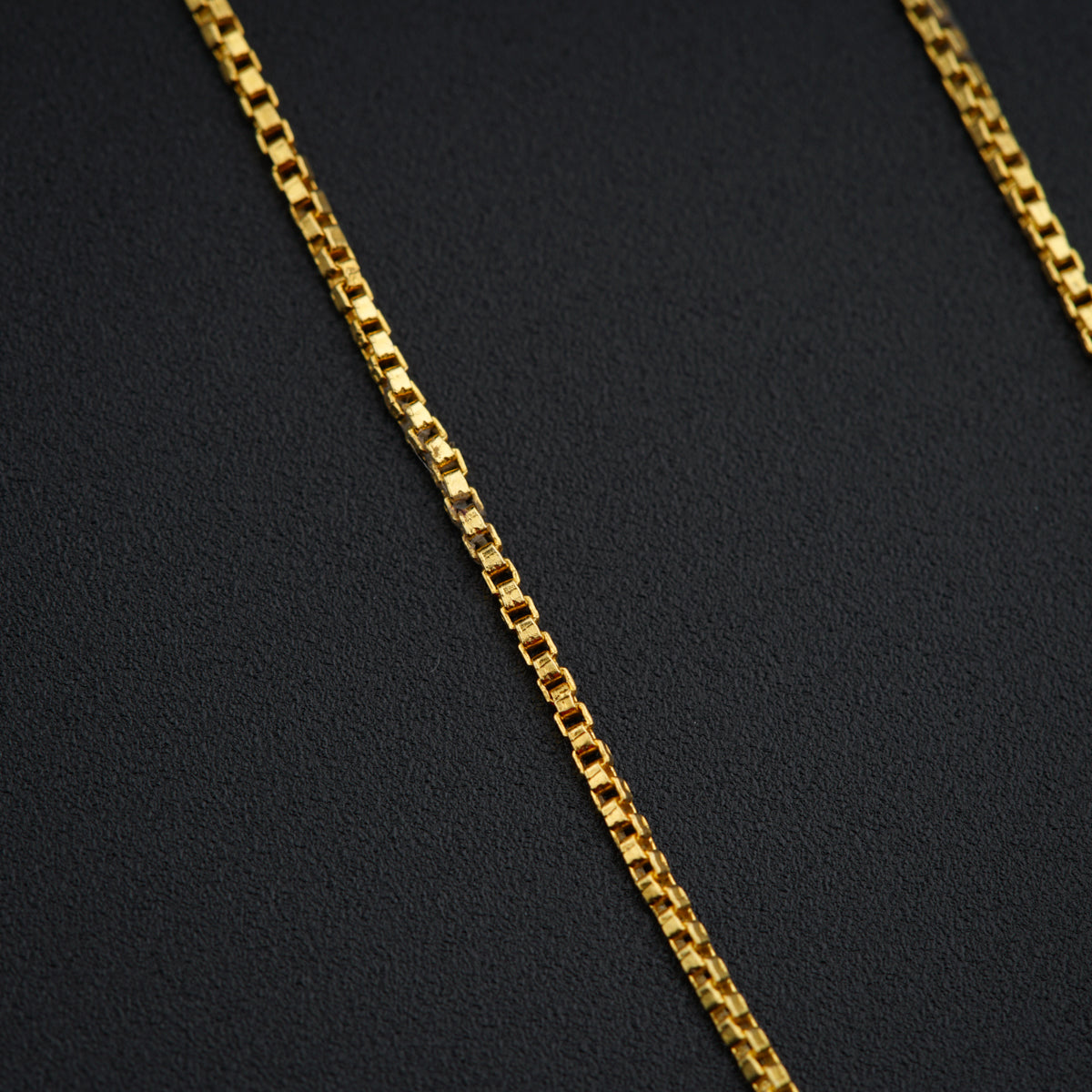 a close up of a gold chain on a black surface