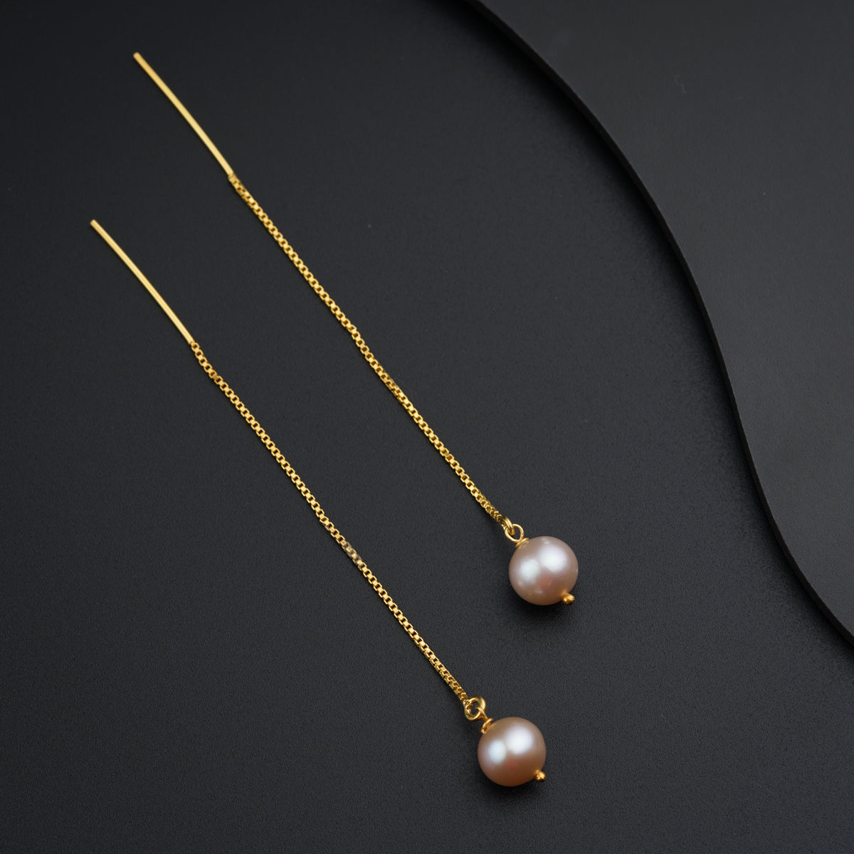 a pair of pearls hanging from a gold chain
