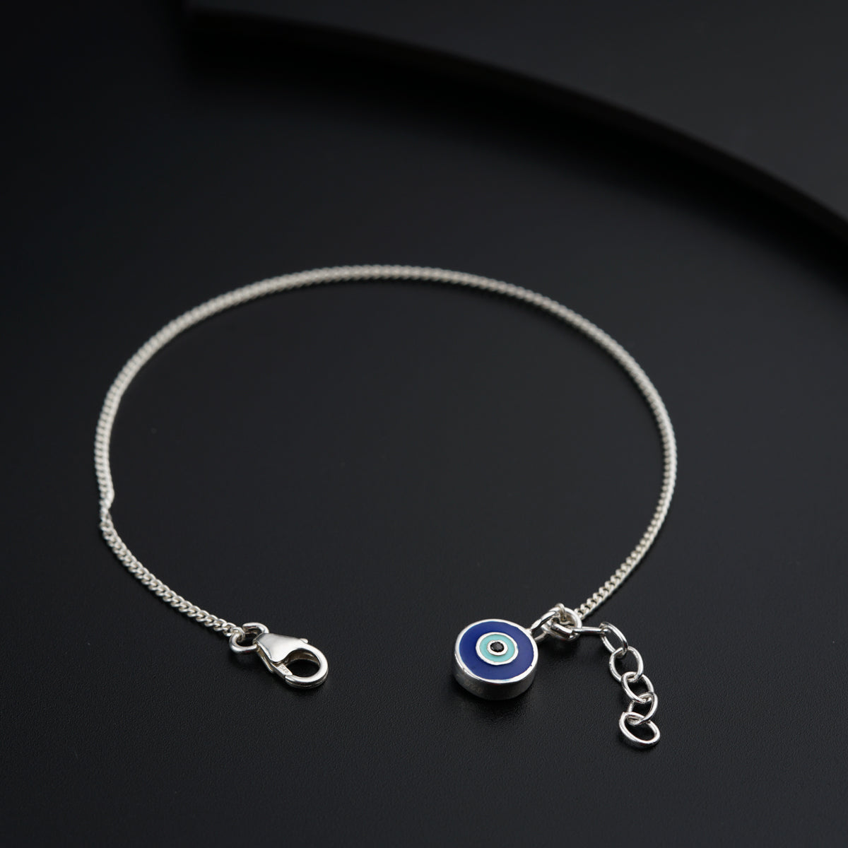 a silver bracelet with a evil eye charm
