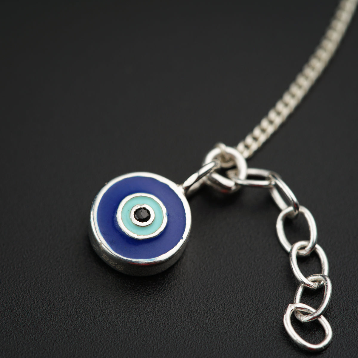 a blue and white evil eye charm on a chain