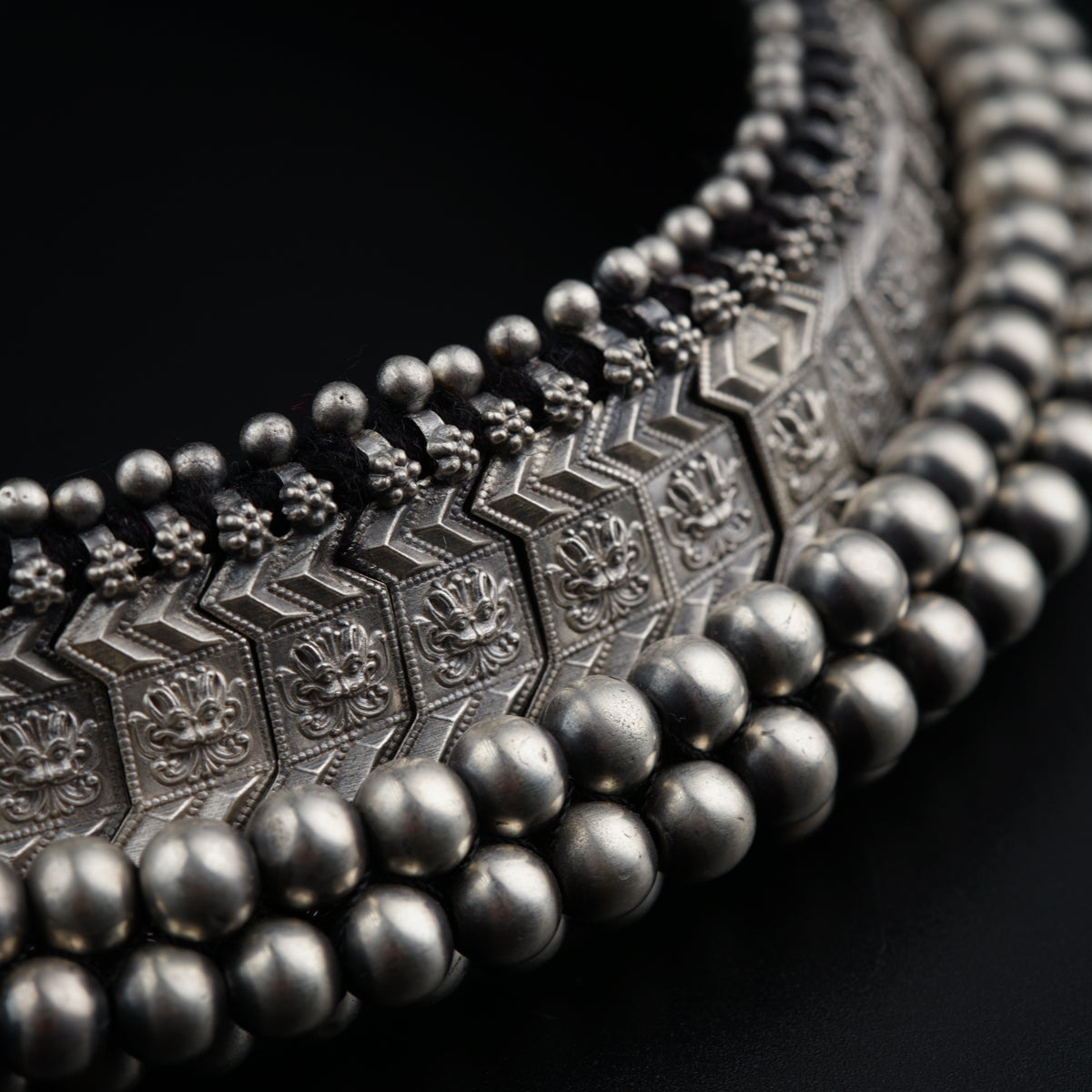 a close up of a beaded necklace on a black background