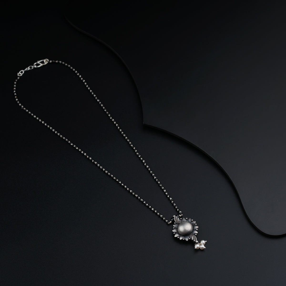 a necklace with pearls and a star on a black background