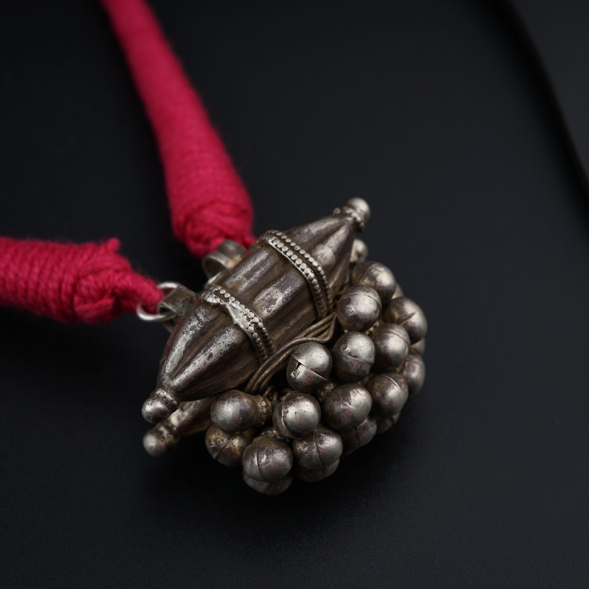 a silver object with a red cord on a black surface