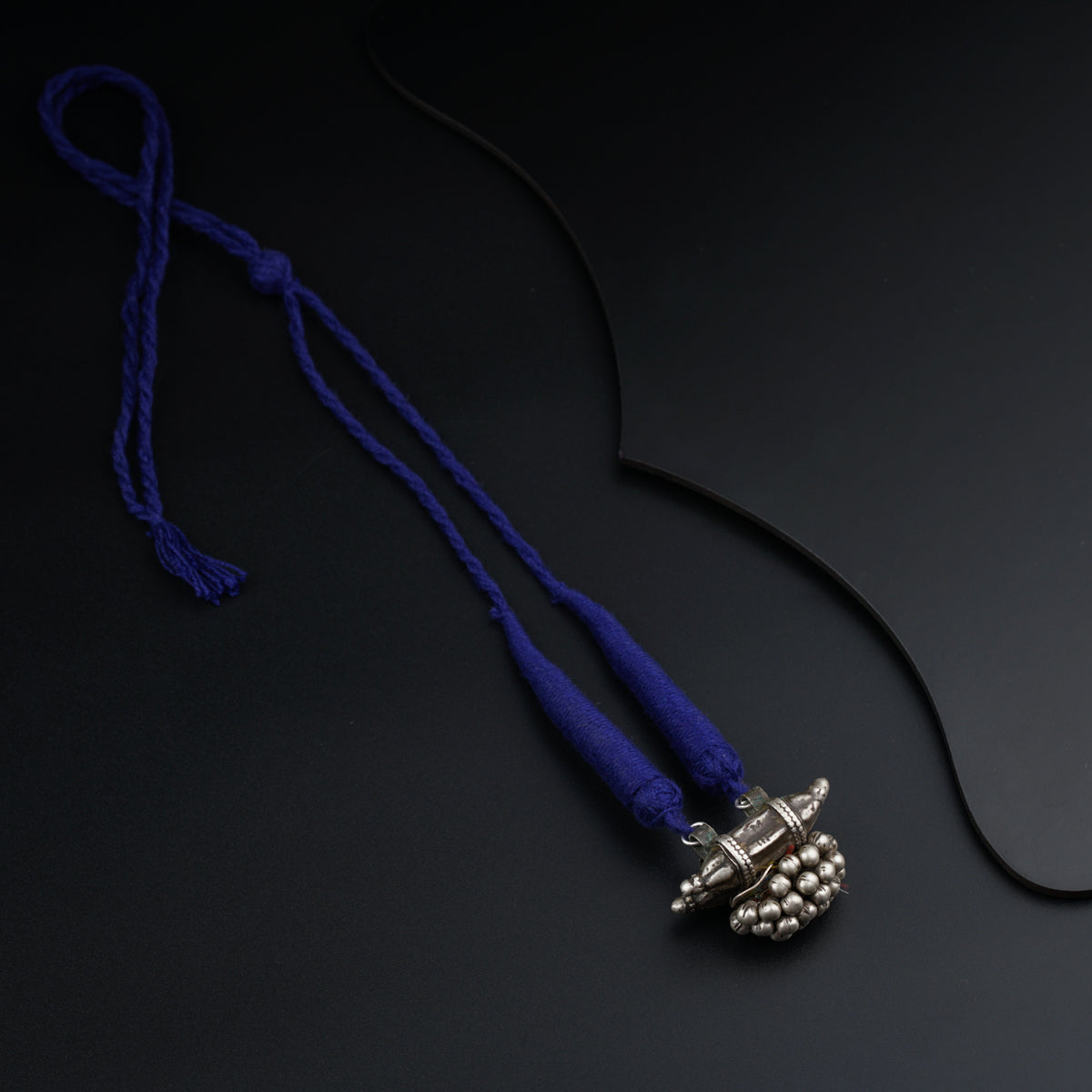 a blue necklace with a silver clasp on a black background