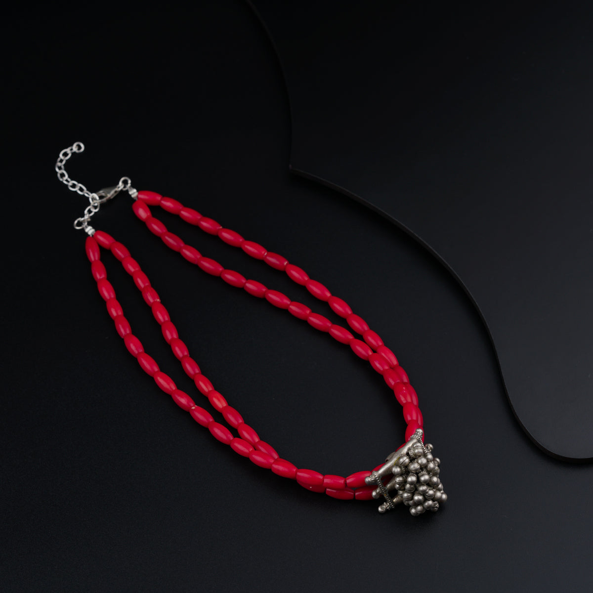 a red necklace with silver beads and a chain