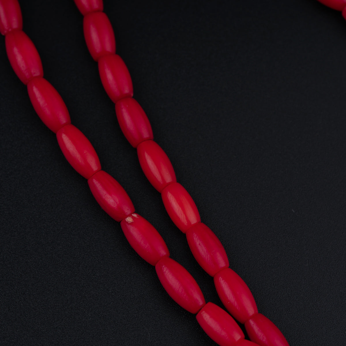 a red bead necklace on a black surface
