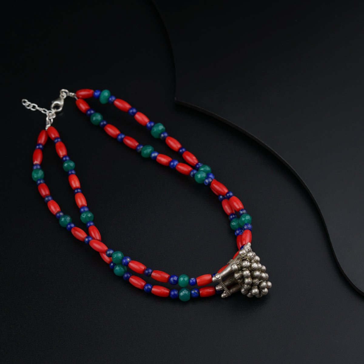 a red, blue and green beaded necklace on a black surface