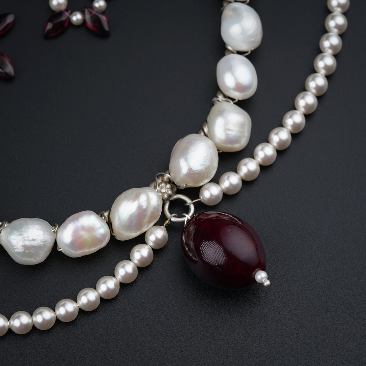 a necklace with pearls and a red stone