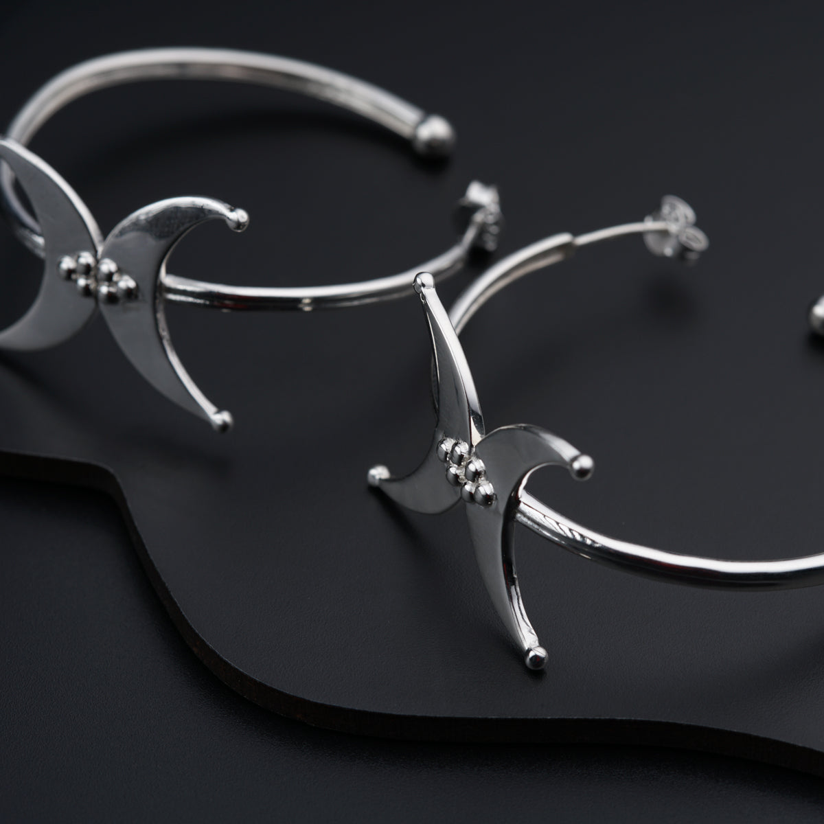 a pair of silver bracelets on a black surface