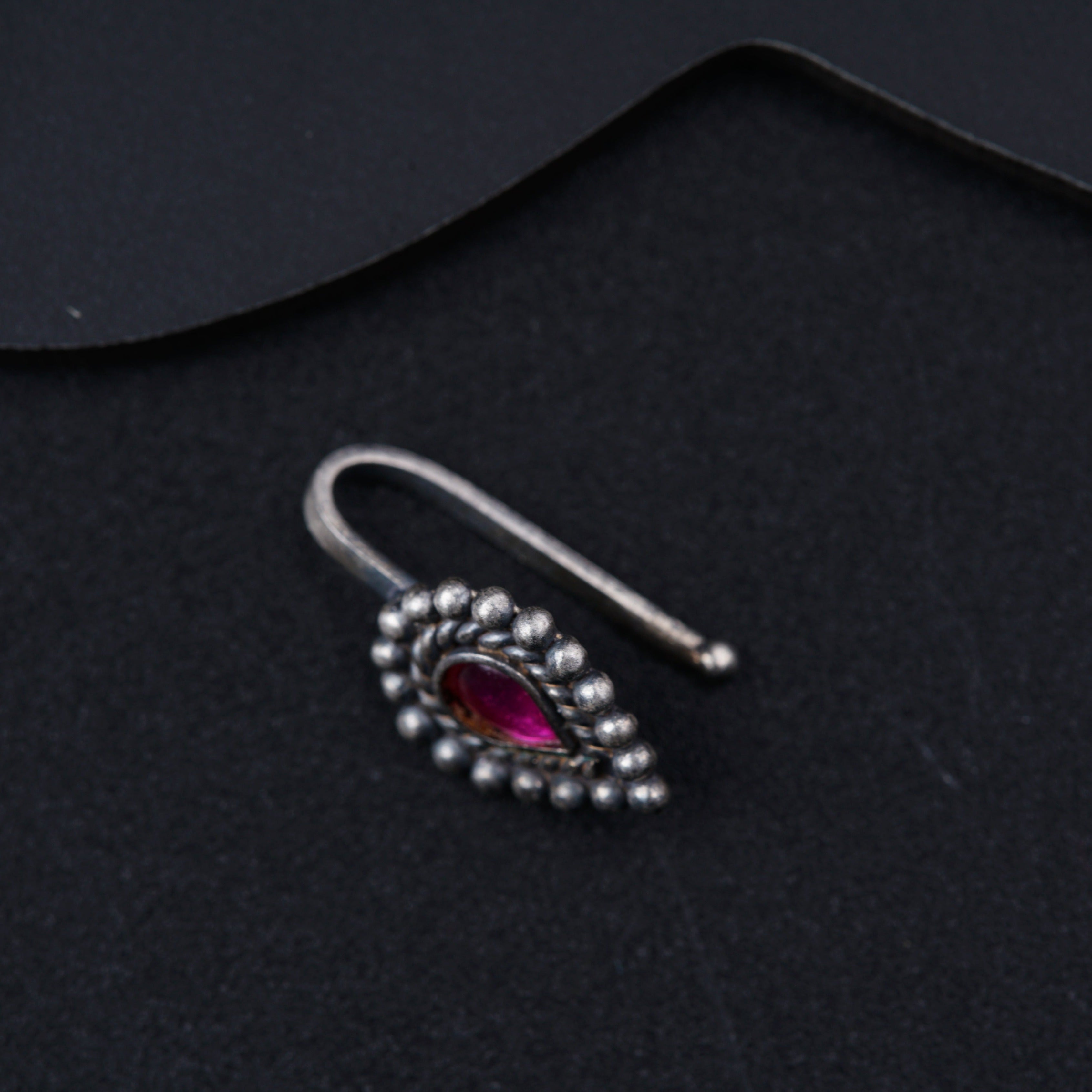 a pair of silver ear clips with a red stone