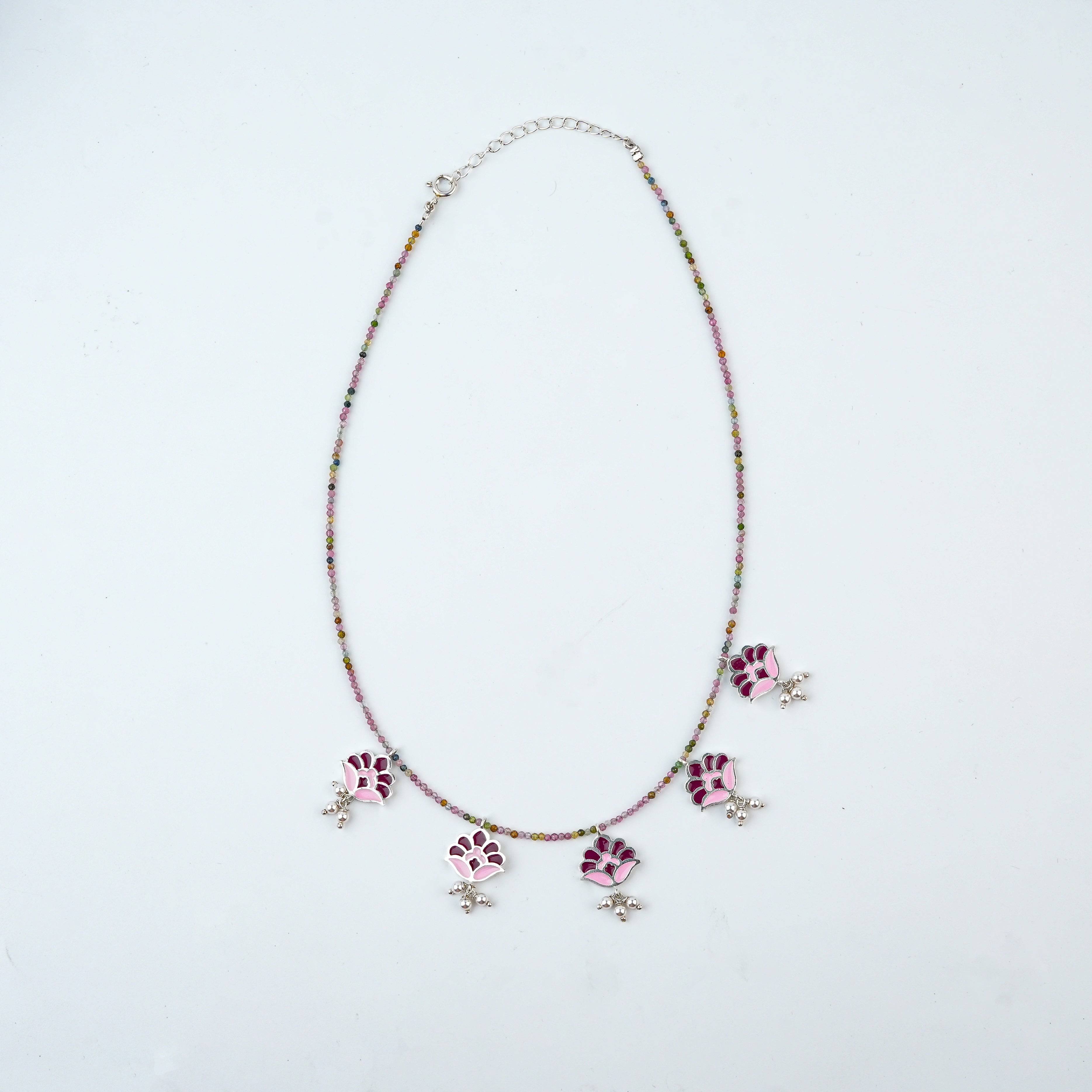 Flat-lay of Enamel Charm Necklace with Tourmaline with colorful charms, natural gemstones, and complementary silver jewellery