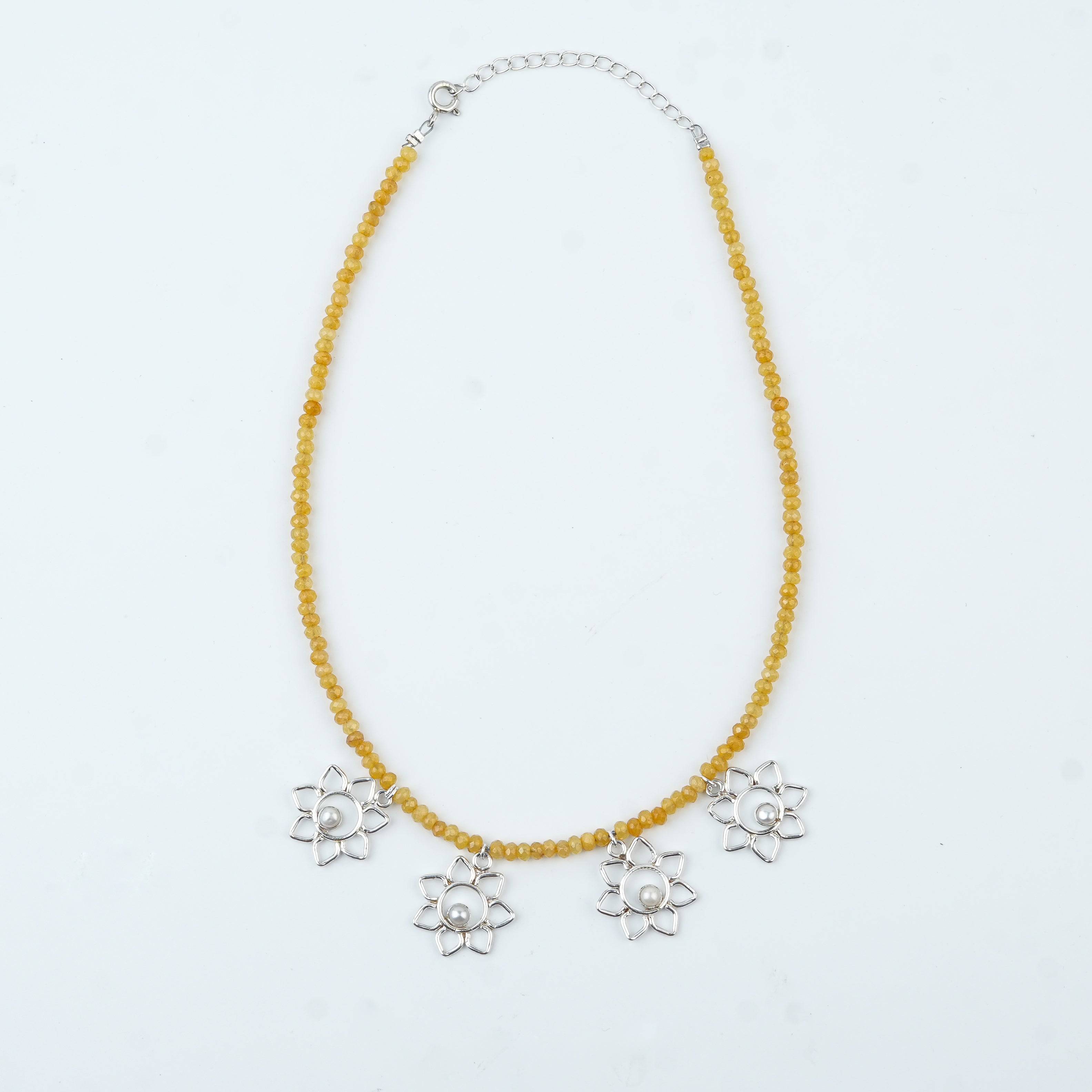 Flat-lay of Flower & Pearl Charm Necklace with Yellow Jade featuring pearls, floral charms, and complementary silver jewellery