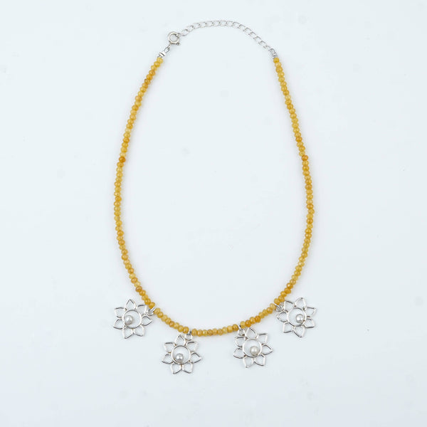 Flat-lay of Flower & Pearl Charm Necklace with Yellow Jade featuring pearls, floral charms, and complementary silver jewellery