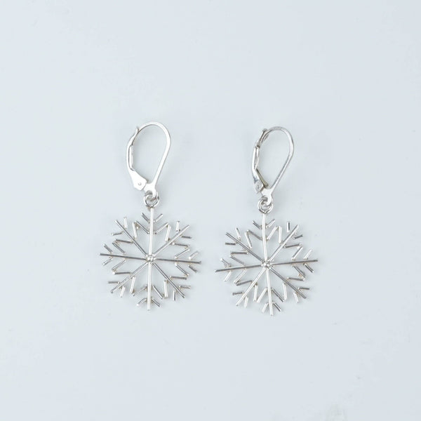 Flat-lay of Silver Snowflake Dangle Earrings with complementary jewellery and elegant styling accessories