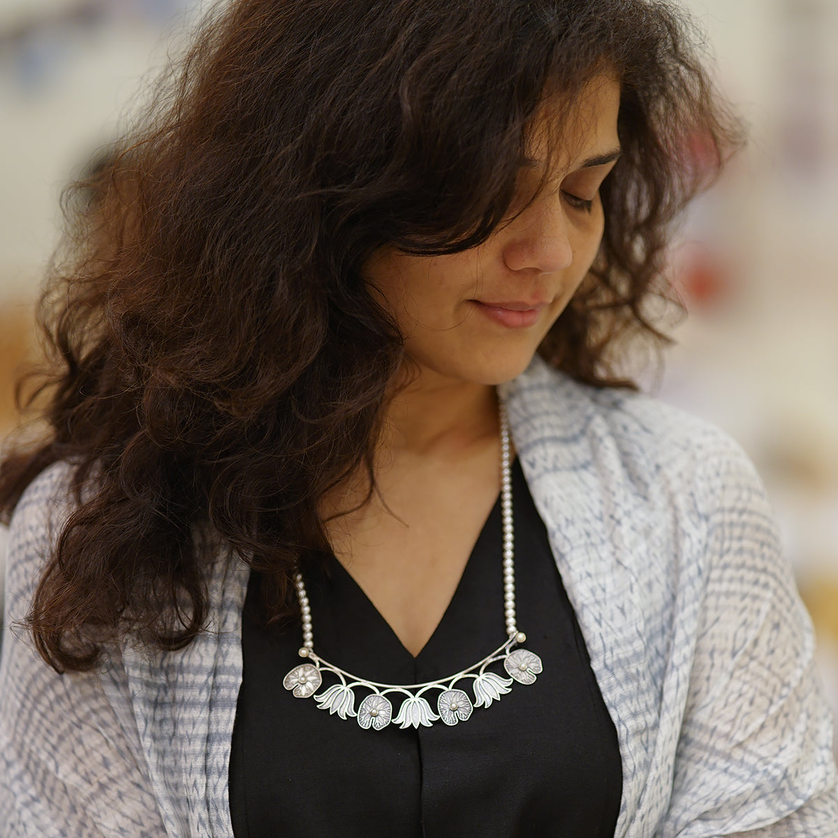 a woman wearing a necklace with flowers on it