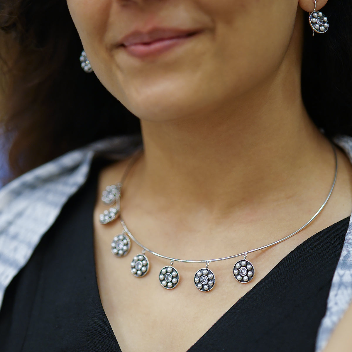 a close up of a woman wearing a necklace and earrings