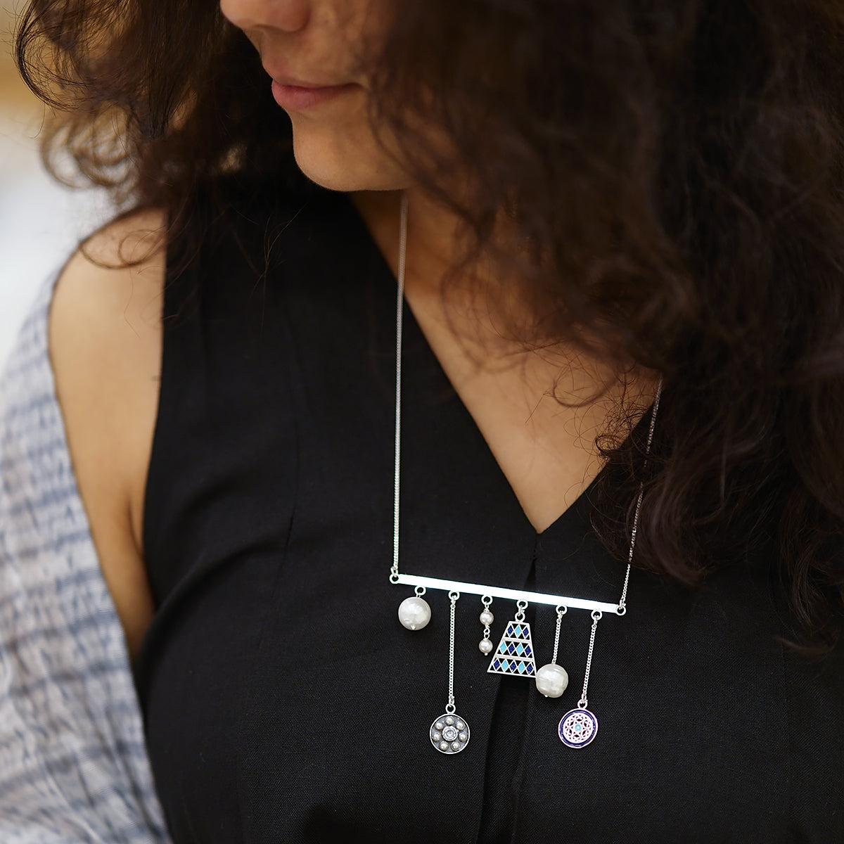 a woman wearing a black top and a white necklace