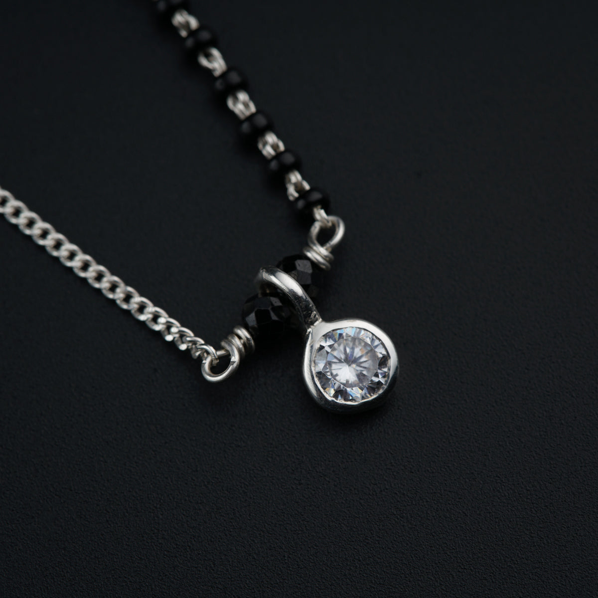 a necklace with a diamond on a black background