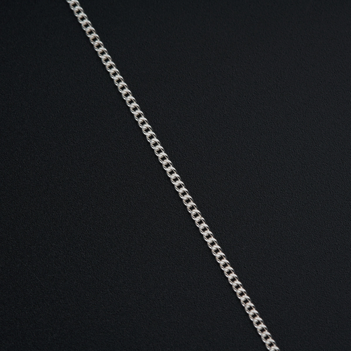 a silver chain is shown on a black surface
