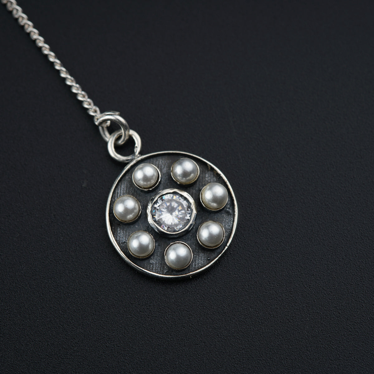 a silver necklace with pearls and a diamond