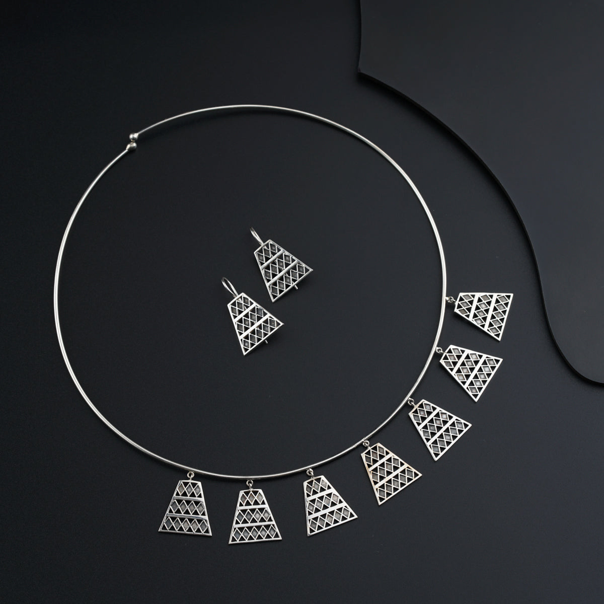 a silver necklace and matching earrings on a black background