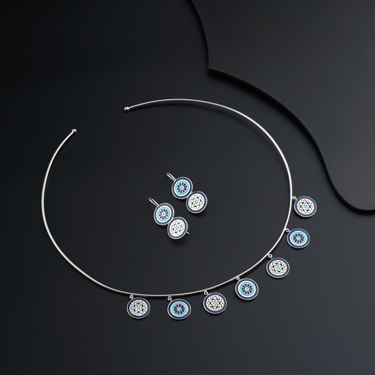 a necklace and earring set on a black surface