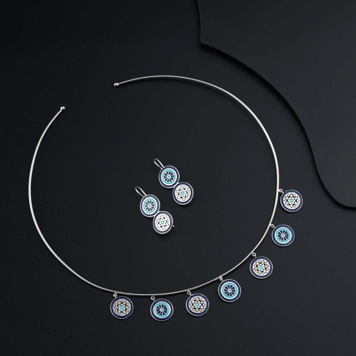 a necklace and earrings on a black surface