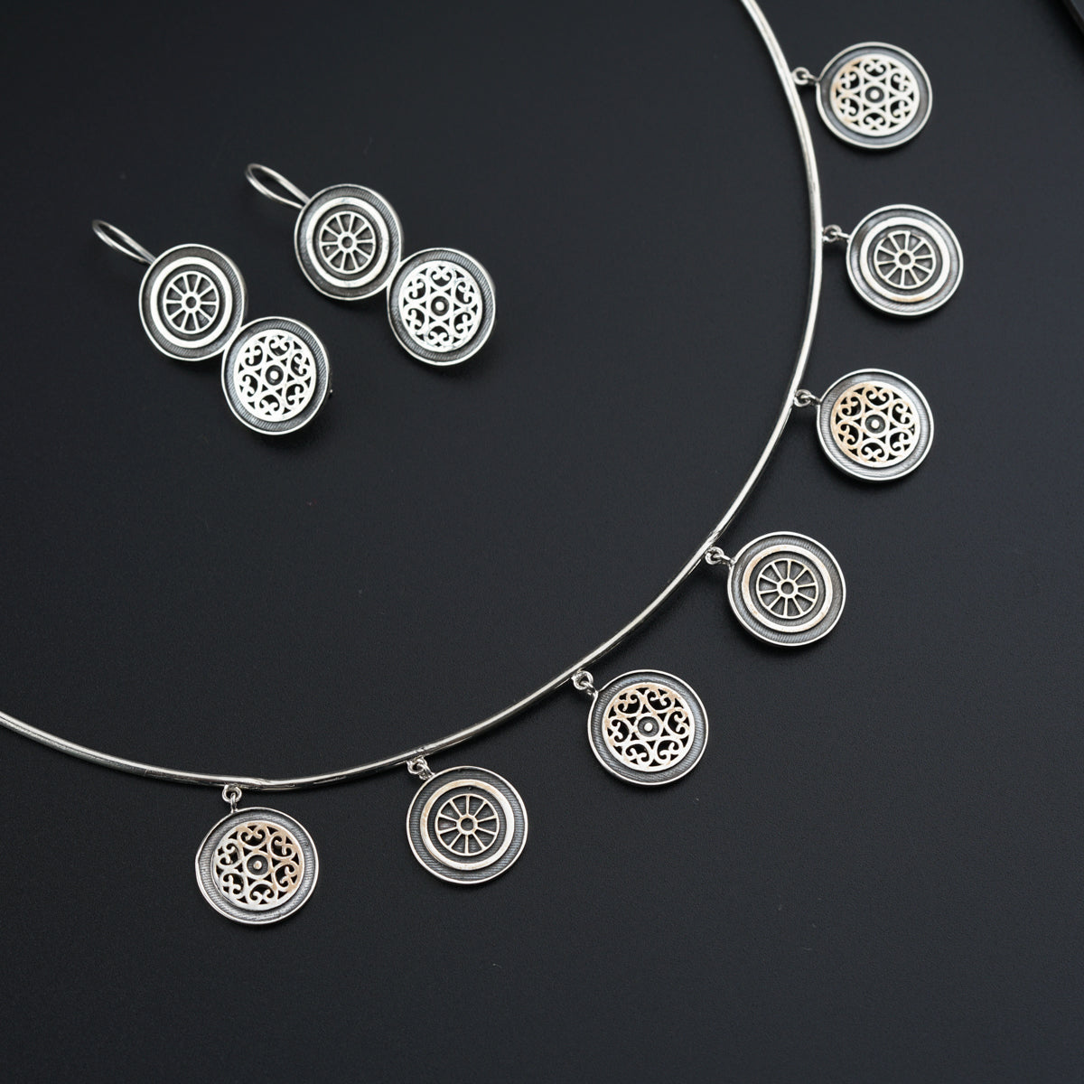 a silver necklace and earring set on a black surface