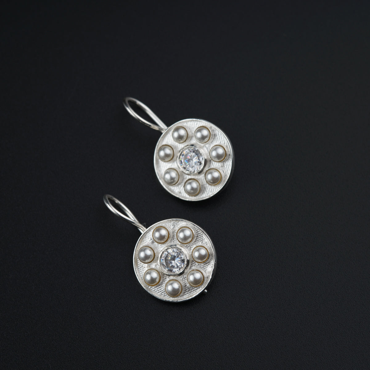 a pair of silver earrings with pearls on them