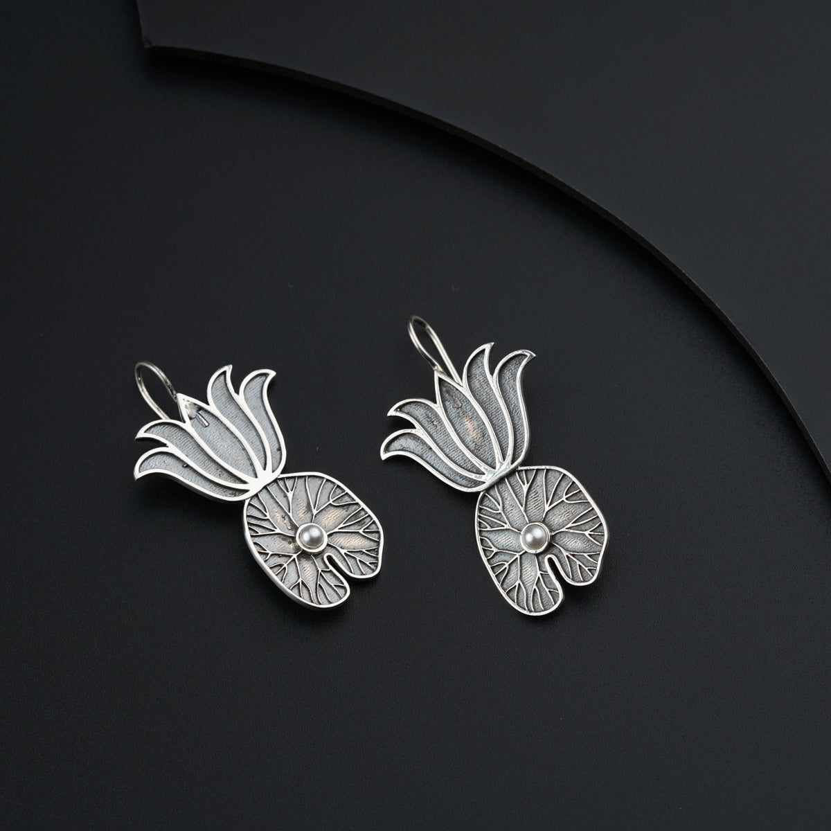 a pair of silver earrings on a black surface